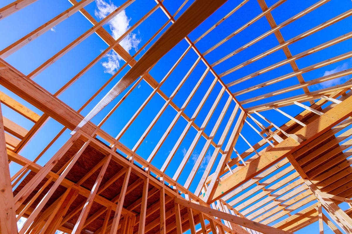 Construction workers building wooden frame for new house